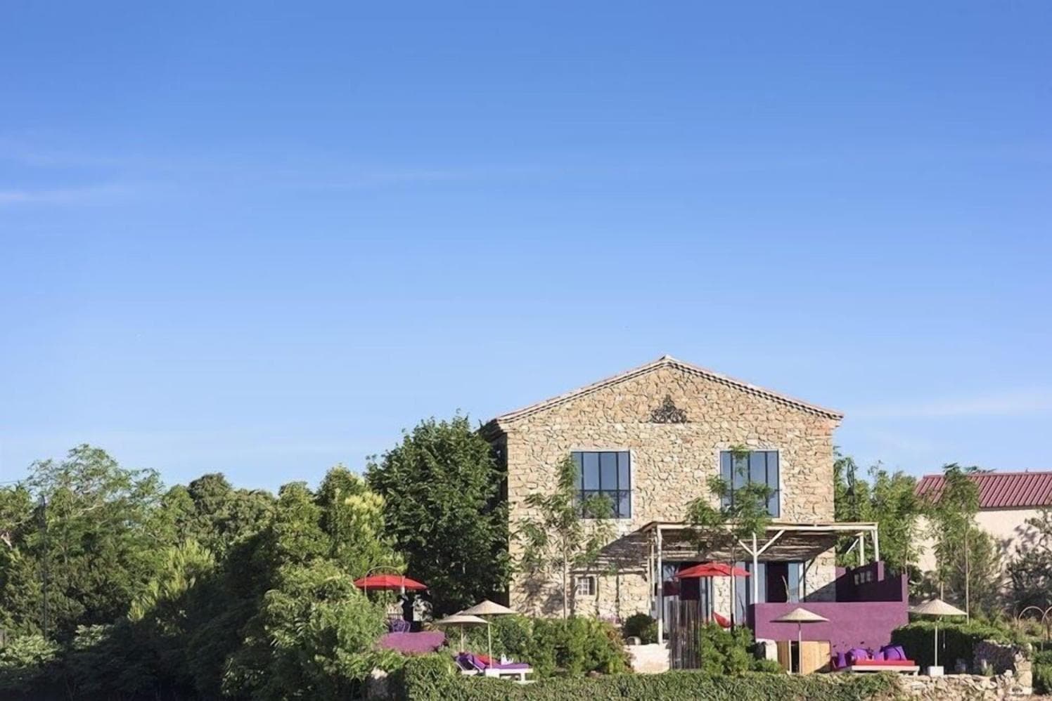 Stone-built Languedoc house with shuttered windows, surrounded by trees and low hills